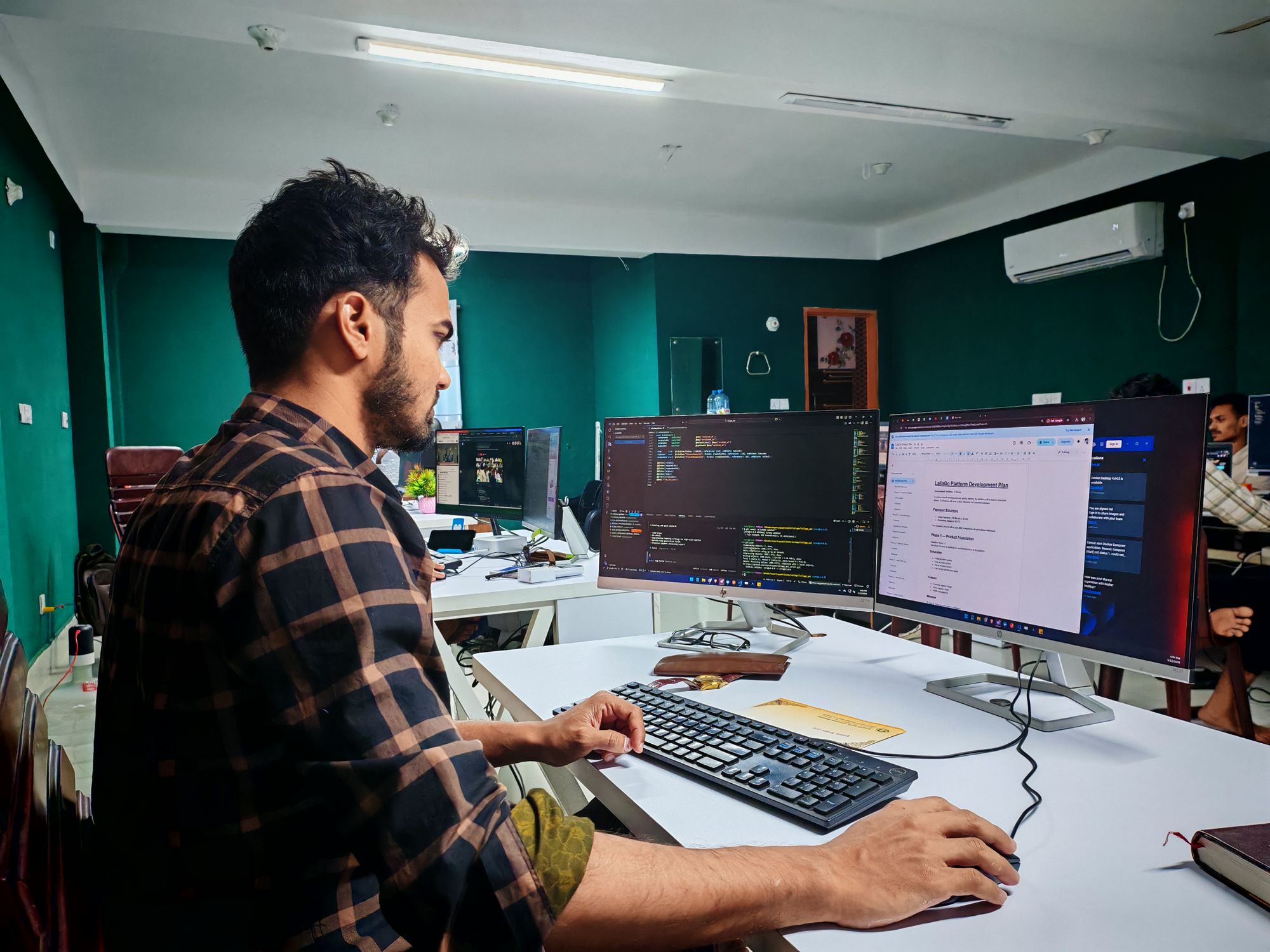 Persona programando frente a dos monitores con código