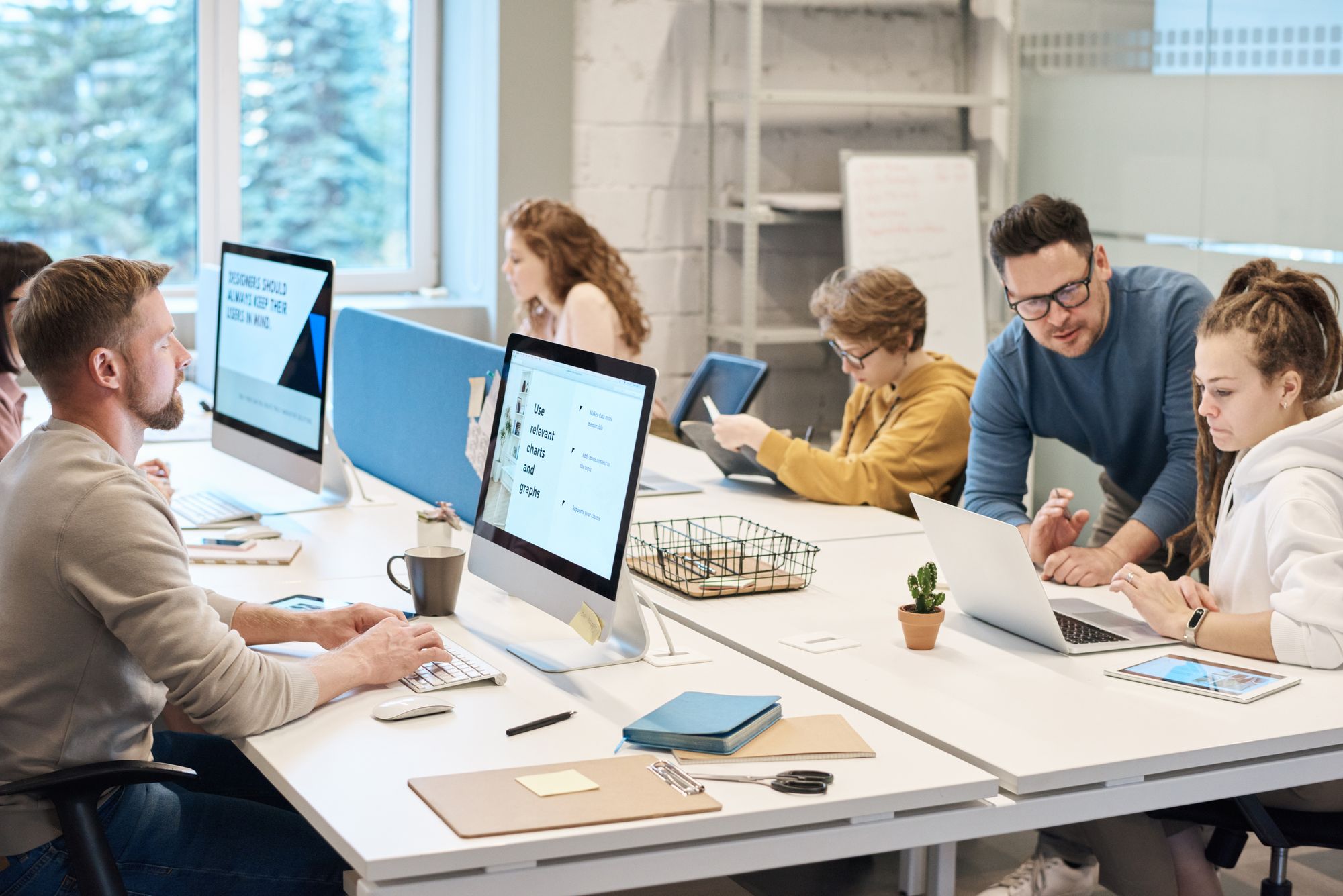 Equipo de trabajo compartiendo una mesa larga con computadoras